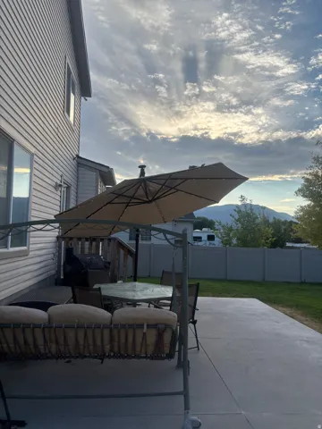 Patio terrace at dusk featuring an outdoor living / dining area, a patio, a fenced backyard, a mountain view, and area for grilling