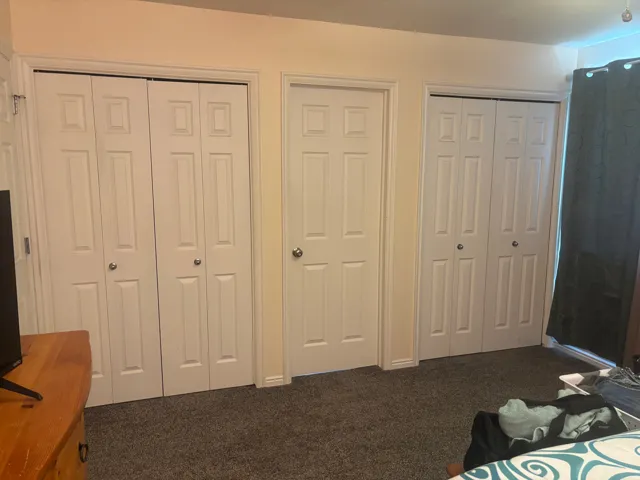 Bedroom featuring multiple closets and dark colored carpet