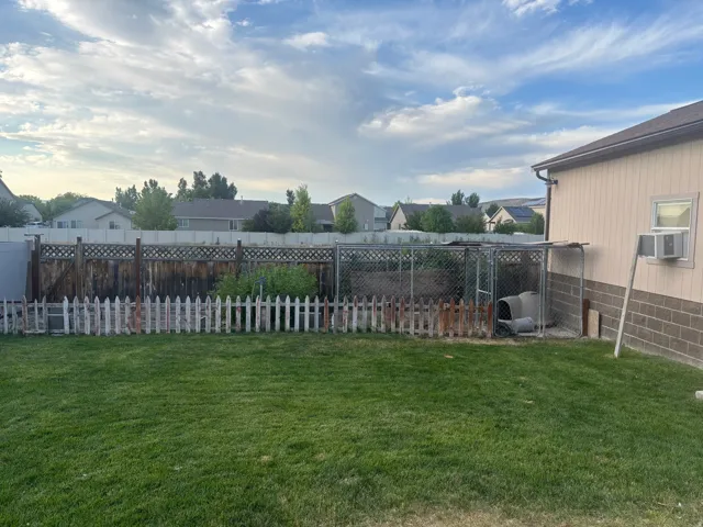 Fenced backyard featuring a residential view and cooling unit