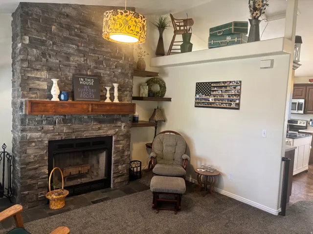 Sitting room with a stone fireplace, dark carpet, and a high ceiling