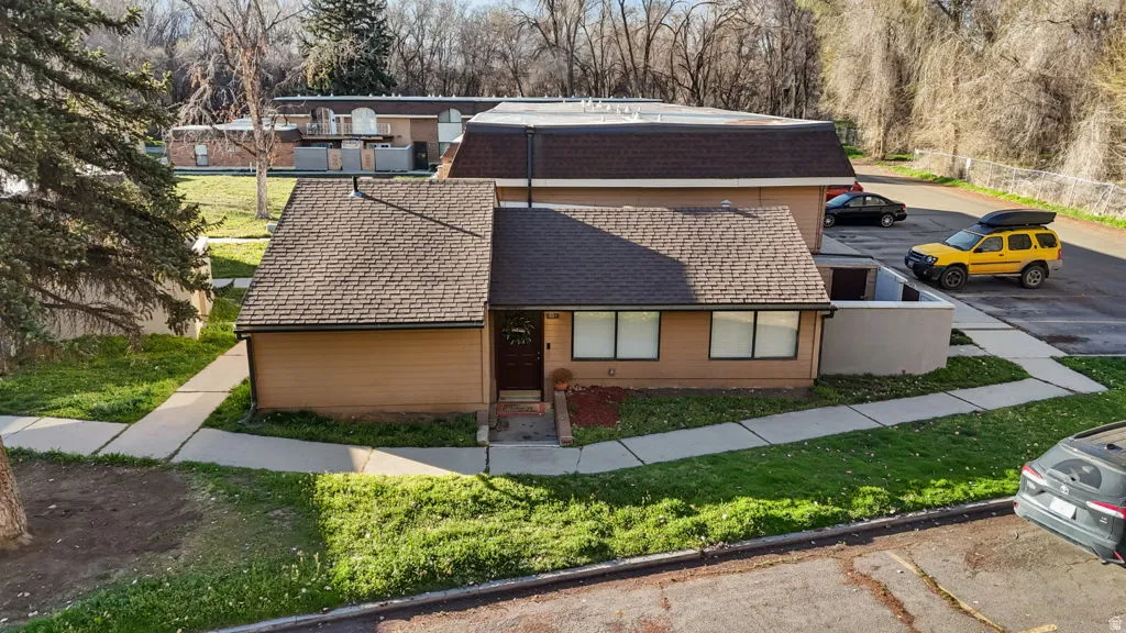View of front of house with a shingled roof and uncovered parking