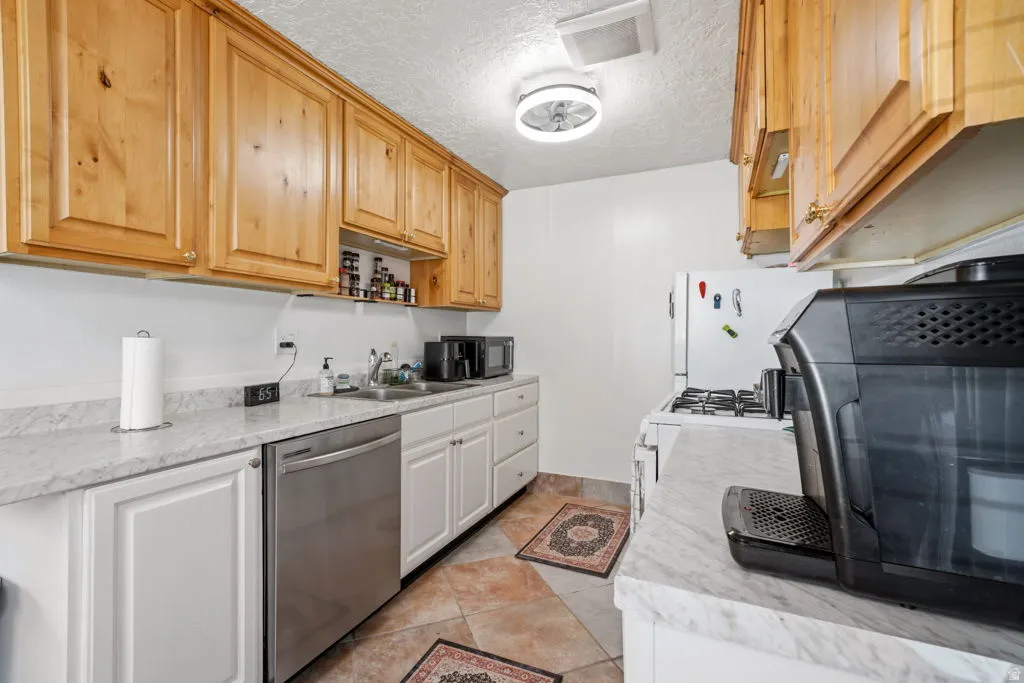 Kitchen with light countertops, stainless steel dishwasher, a textured ceiling, open shelves, and black microwave