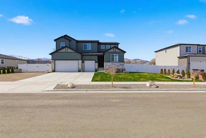 View of front of property featuring a gate, a mountain view, a garage, concrete driveway, and stone siding