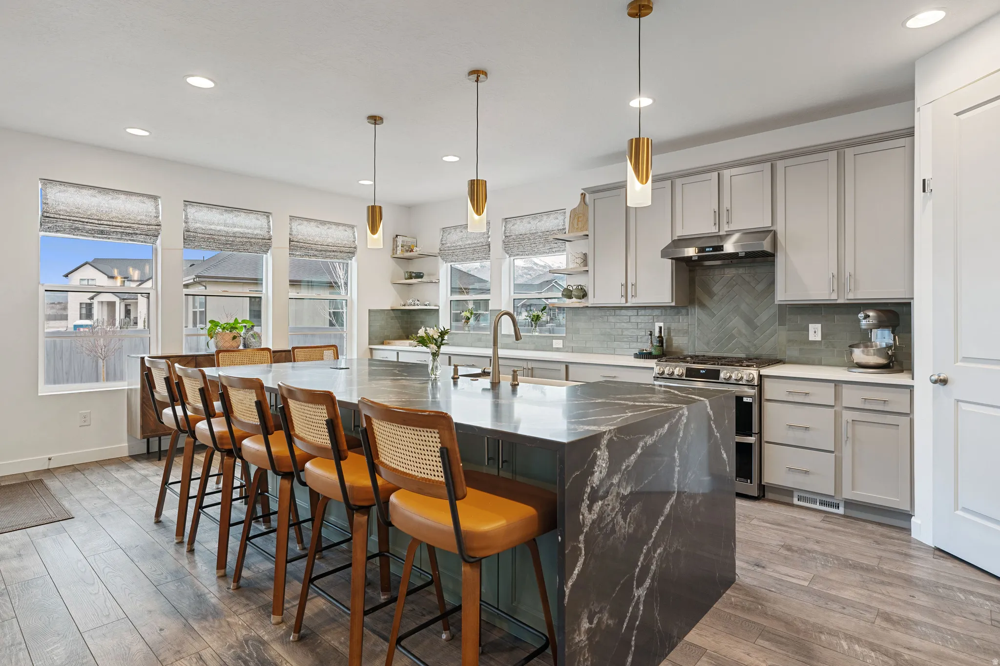 Kitchen featuring gray cabinets, double oven range, a breakfast bar, open shelves, and decorative light fixtures