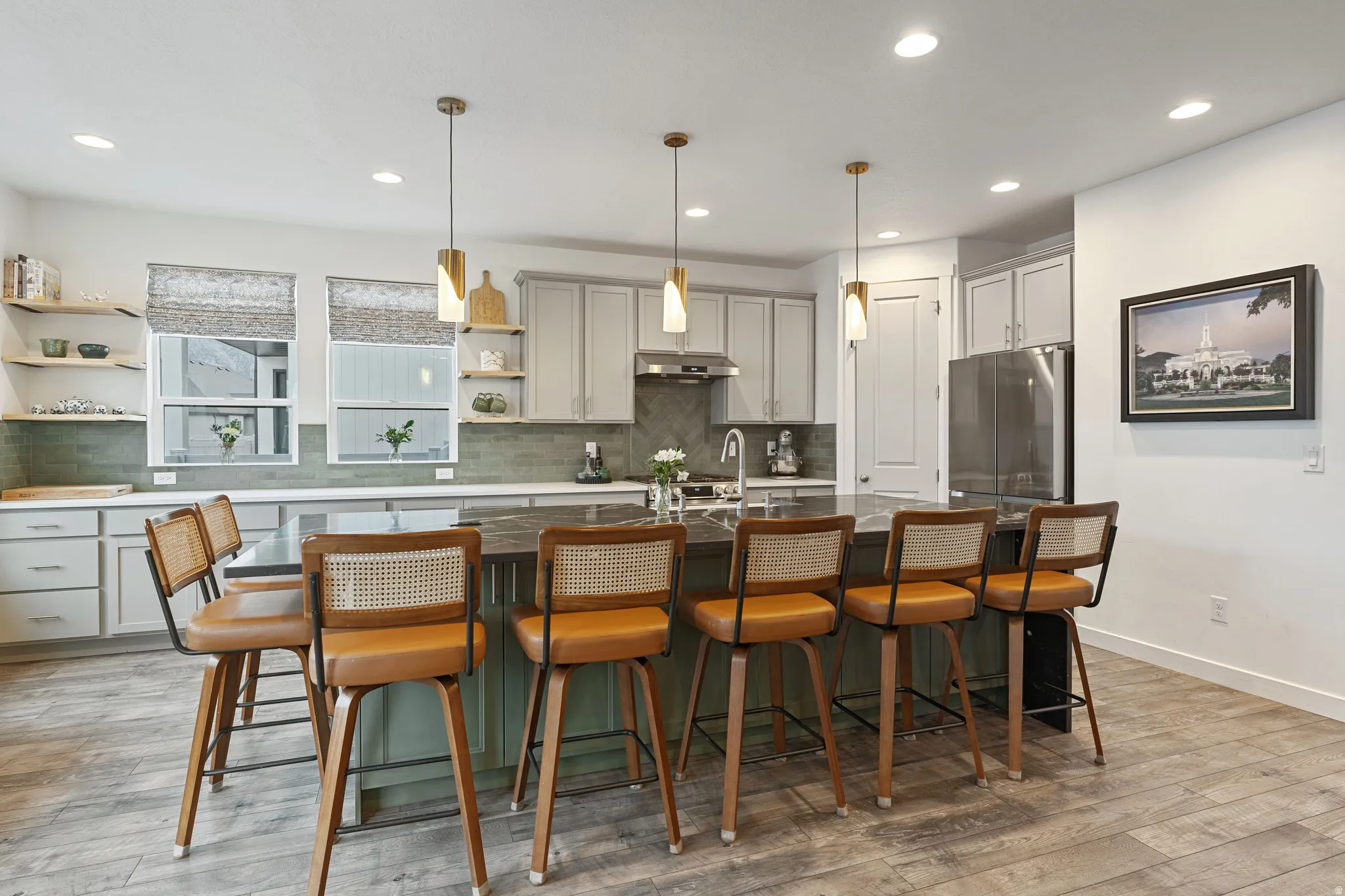 Kitchen with a breakfast bar area, pendant lighting, light wood-type flooring, an island with sink, and freestanding refrigerator