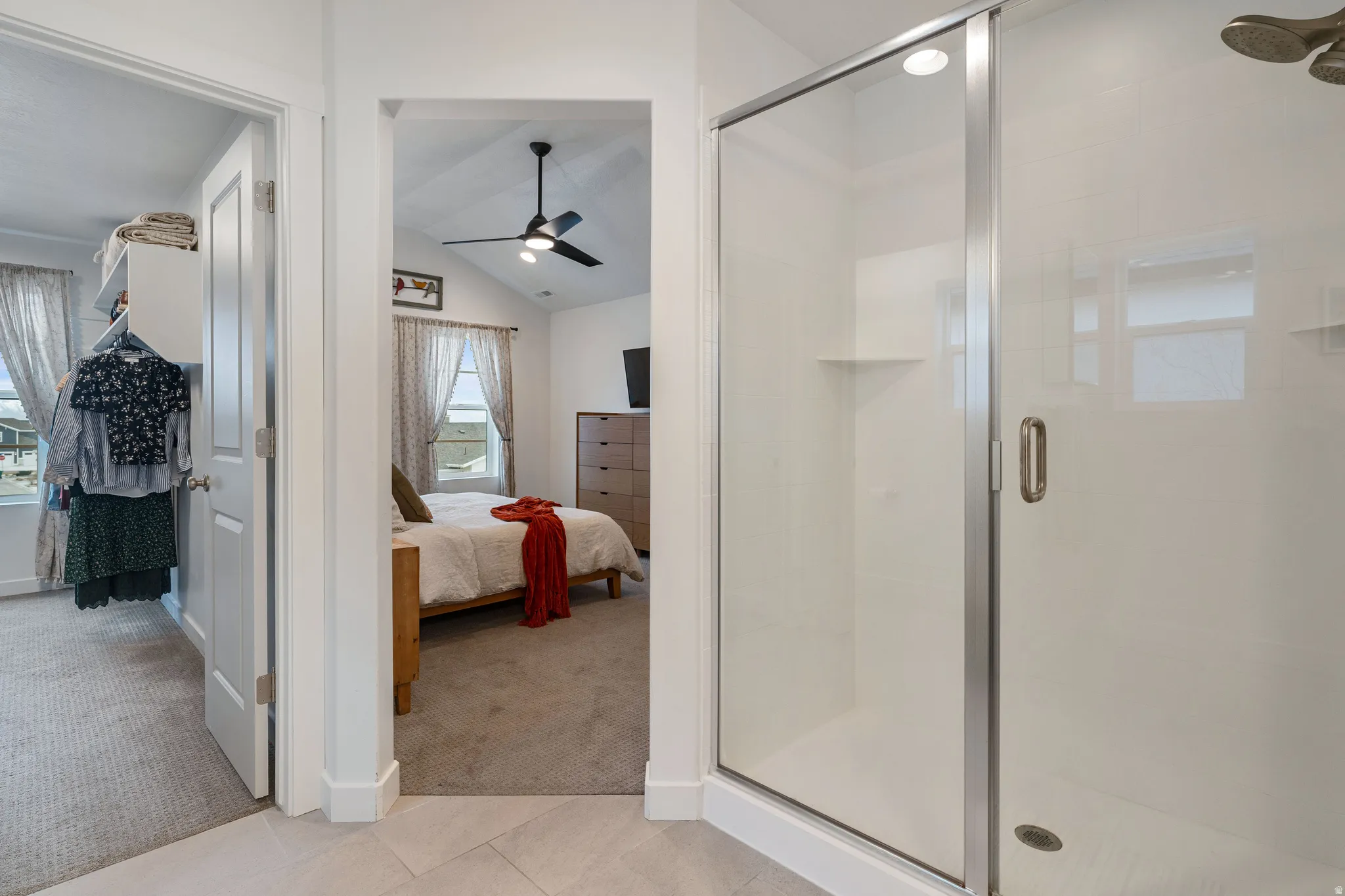 Primary Full bath with ensuite bath, vaulted ceiling, light carpet, a shower stall, and a ceiling fan