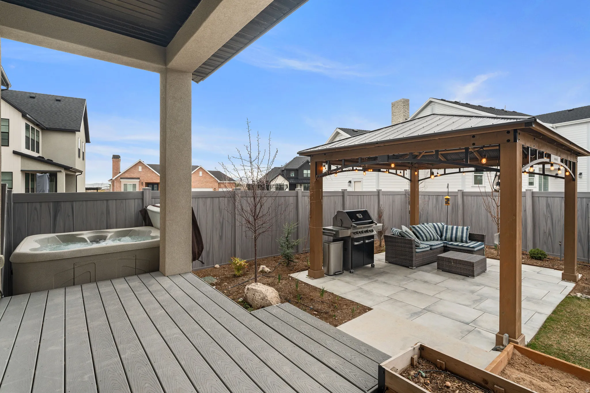 Wooden terrace with an outdoor lounge area, a patio area, a gazebo, a fenced backyard, and grilling area