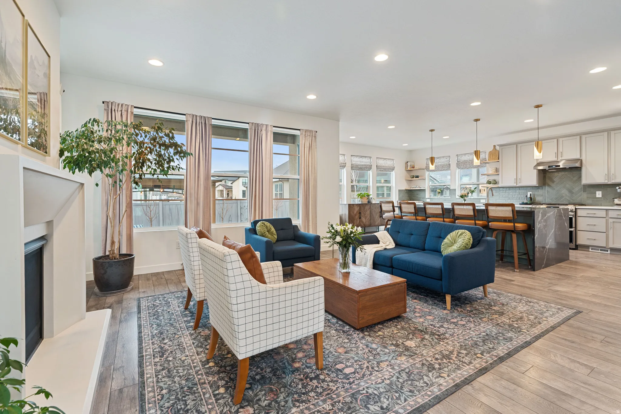 Living room with a fireplace with raised hearth, light wood-type flooring, and recessed lighting