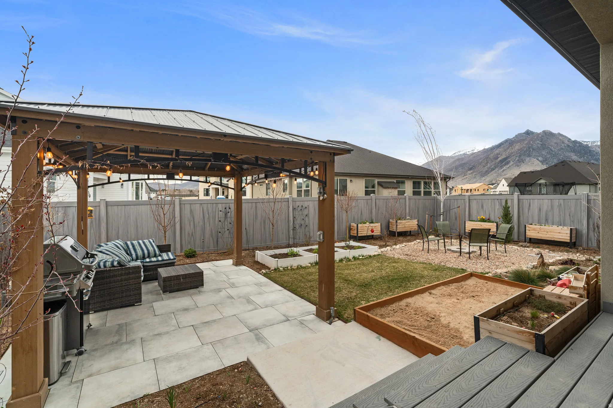 Fenced backyard with a patio, a garden, an outdoor hangout area, area for grilling, and a gazebo