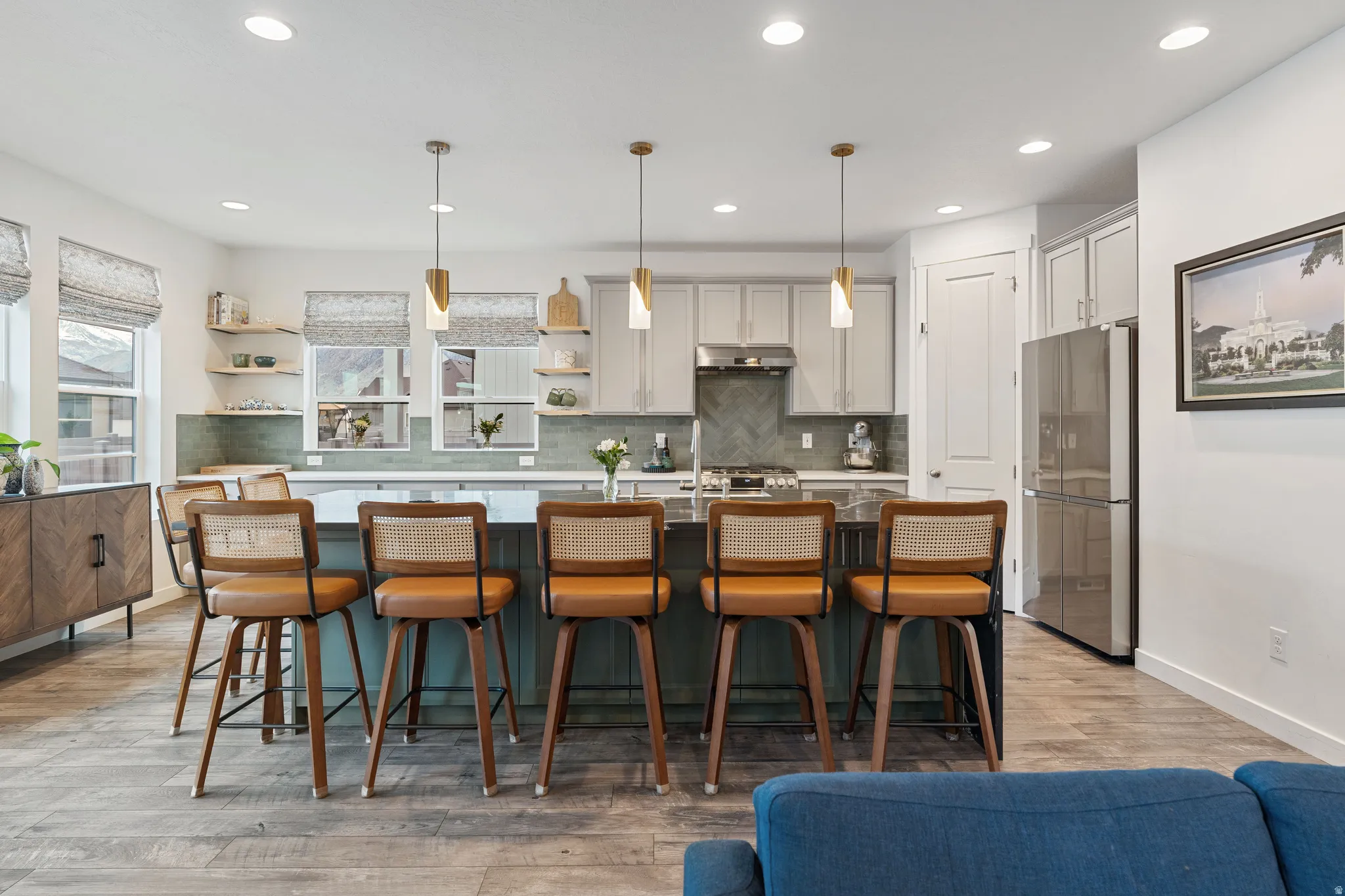 Kitchen featuring a breakfast bar area, decorative light fixtures, an island with sink, and stainless steel appliances