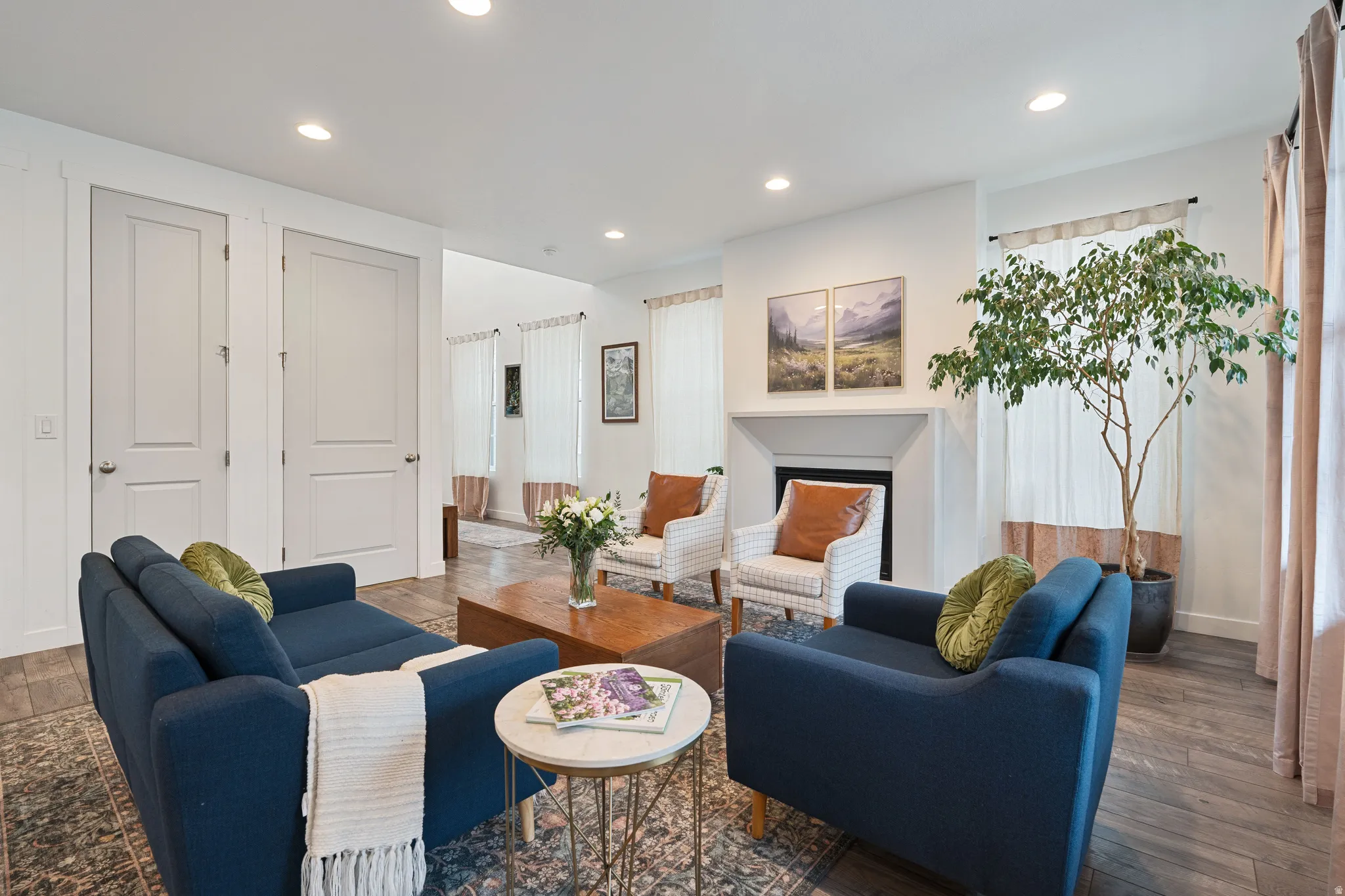 Living room with wood finished floors, recessed lighting, and a fireplace