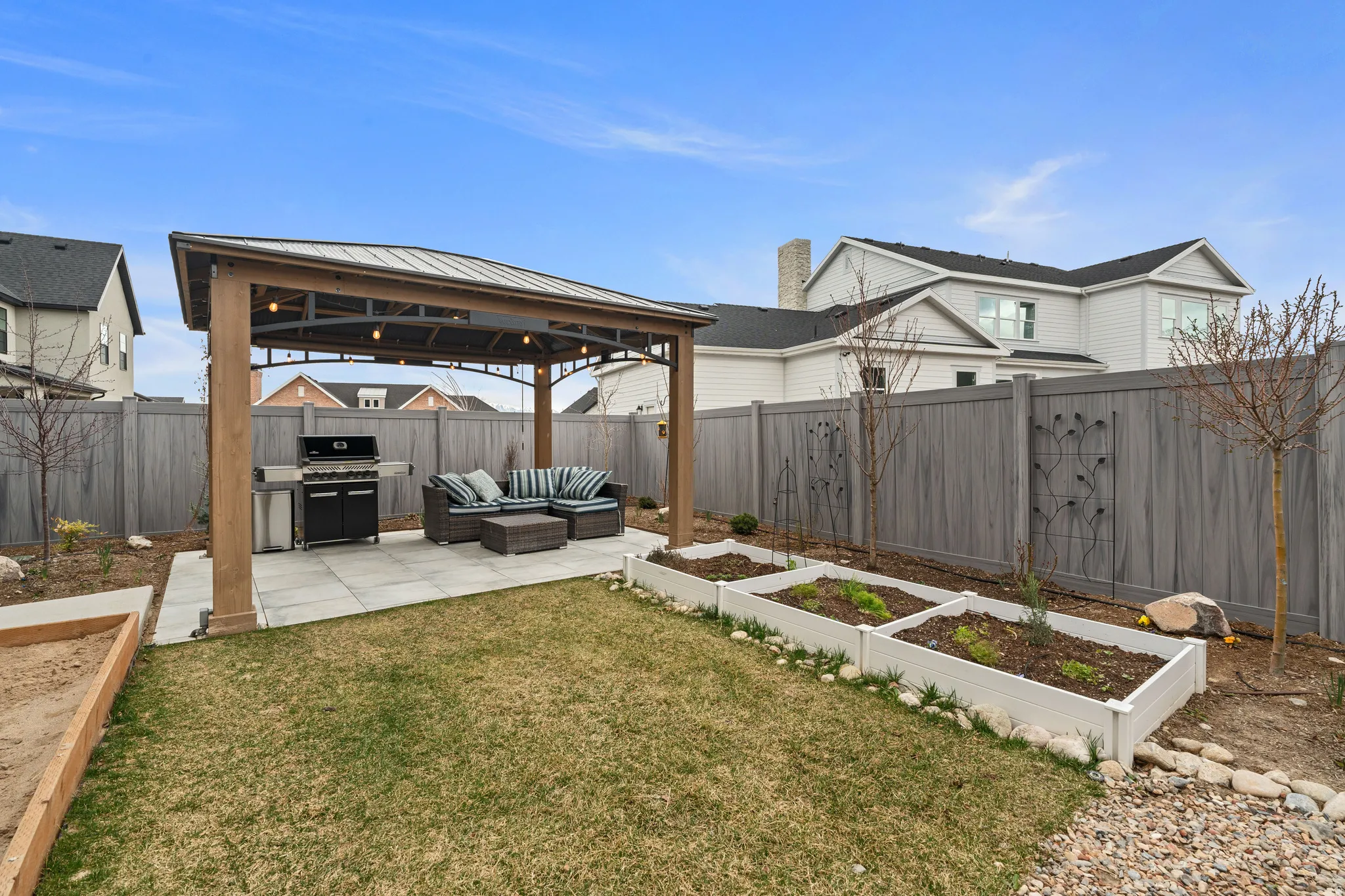 Fenced backyard featuring a gazebo, a vegetable garden, a patio, and an outdoor hangout area