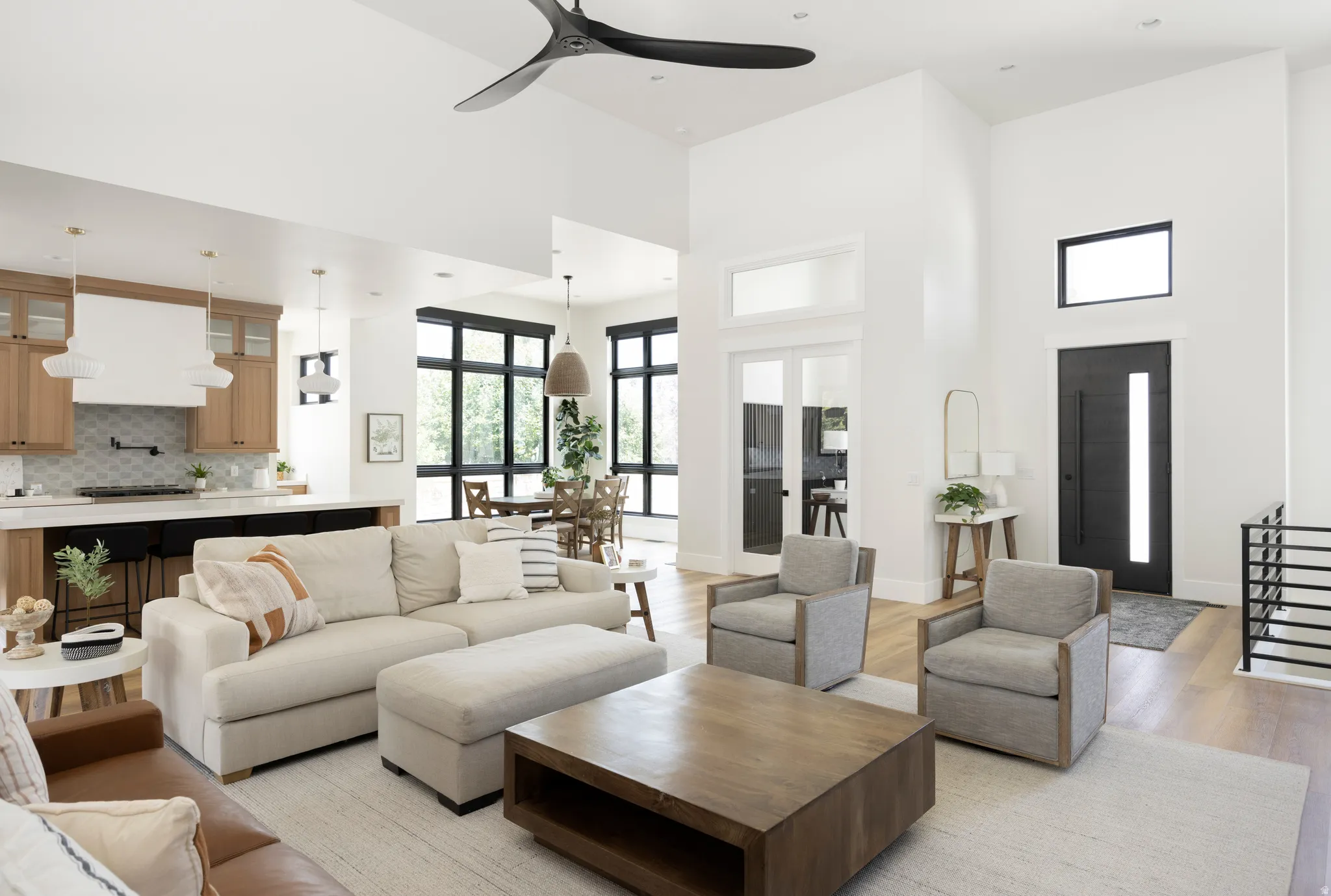 Living area with a ceiling fan, a high ceiling, and light wood-style flooring
