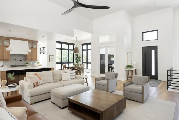 Living area with a ceiling fan, a high ceiling, and light wood-style flooring
