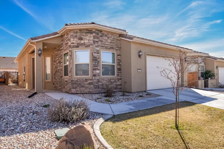 View of front of property featuring a garage, stone siding, stucco siding, and driveway