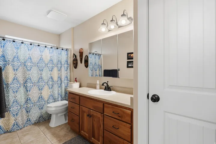 Full bath with vanity, curtained shower, and light tile patterned floors