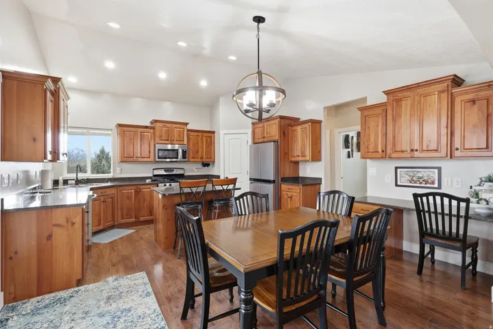 Dining room with vaulted ceiling, dark wood-type flooring, and suspended lighting