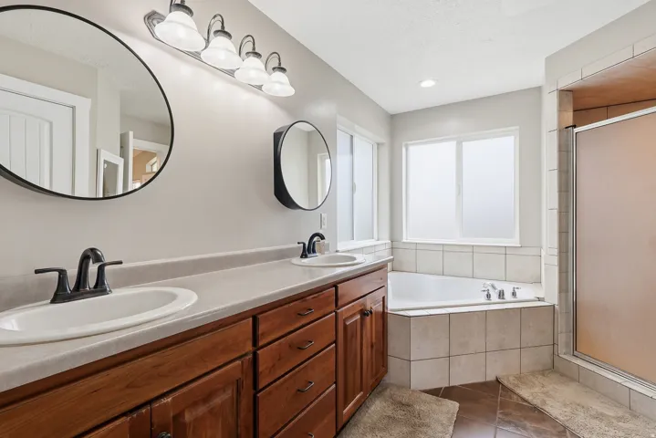 Bathroom with double vanity, a stall shower, a bath, and dark tile patterned floors