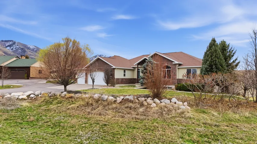 Ranch-style home with a garage, concrete driveway, brick siding, a front lawn, and roof with shingles