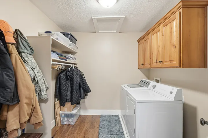 Laundry area with a textured ceiling, light wood-style flooring, washing machine and dryer, and cabinet space