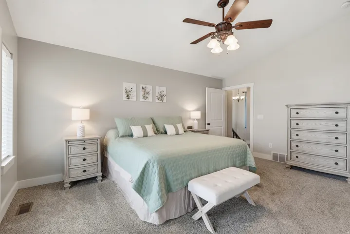 Bedroom featuring vaulted ceiling, light carpet, and a ceiling fan