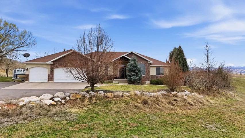 Ranch-style house featuring an attached garage, brick siding, driveway, and a front lawn