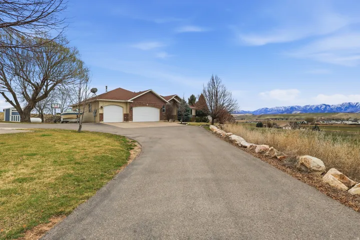View of front facade featuring a garage, asphalt driveway, a mountain view, and brick siding