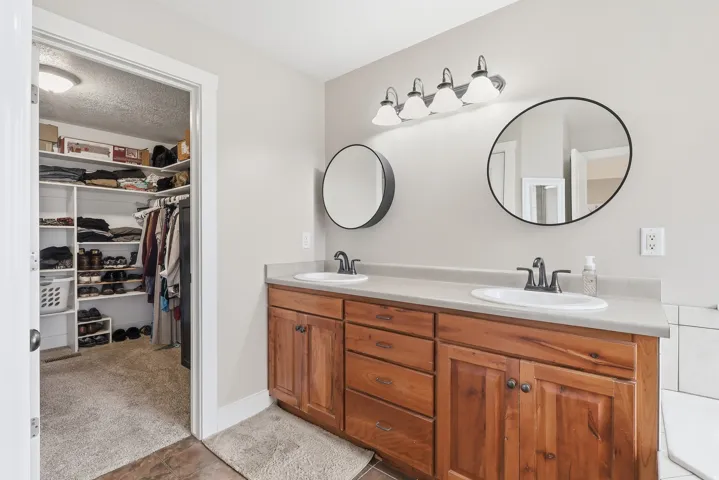 Full bathroom with double vanity, a spacious closet, a textured ceiling, and light colored carpet