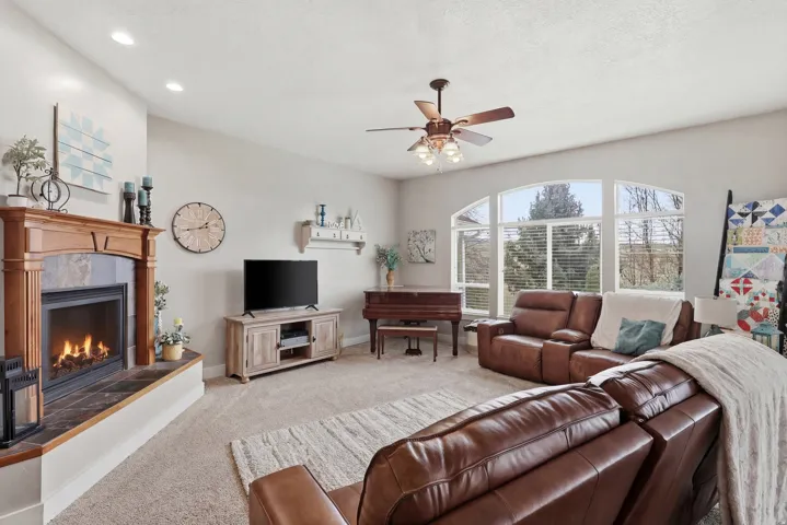 Living room with light colored carpet, a fireplace, ceiling fan, and recessed lighting