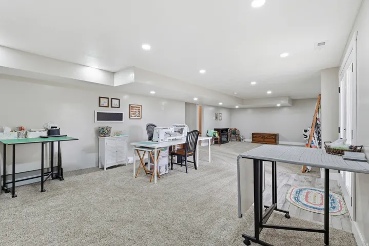 Home office with light colored carpet and recessed lighting