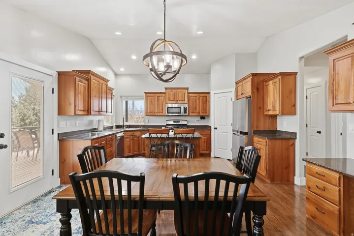 Dining space with vaulted ceiling, a chandelier, and dark wood-style flooring