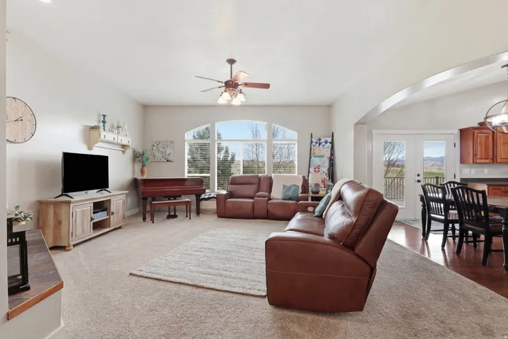 Carpeted living room with a ceiling fan, french doors, and arched walkways