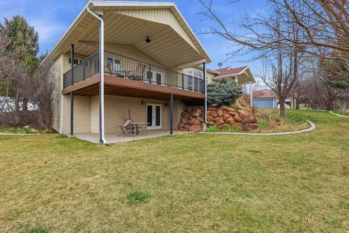 Rear view of property featuring a wooden deck, a patio area, a lawn, and french doors