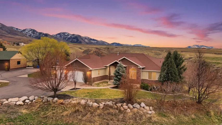 Ranch-style home featuring driveway, a lawn, and a mountain view
