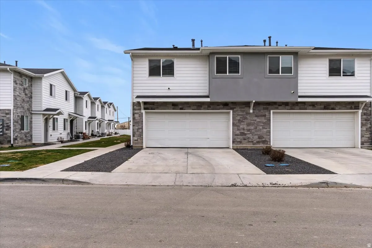 View of front facade with driveway, an attached garage, and a residential view