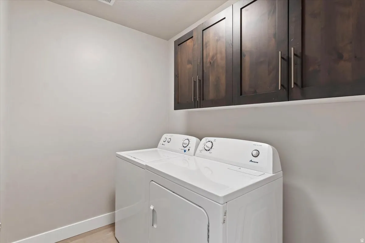 Laundry area featuring cabinet space, washing machine and dryer, and light wood finished floors