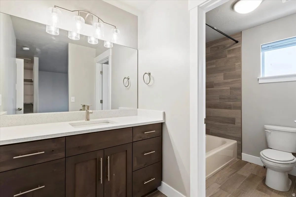 Bathroom featuring vanity, light wood-style flooring, washtub / shower combination, and a spacious closet