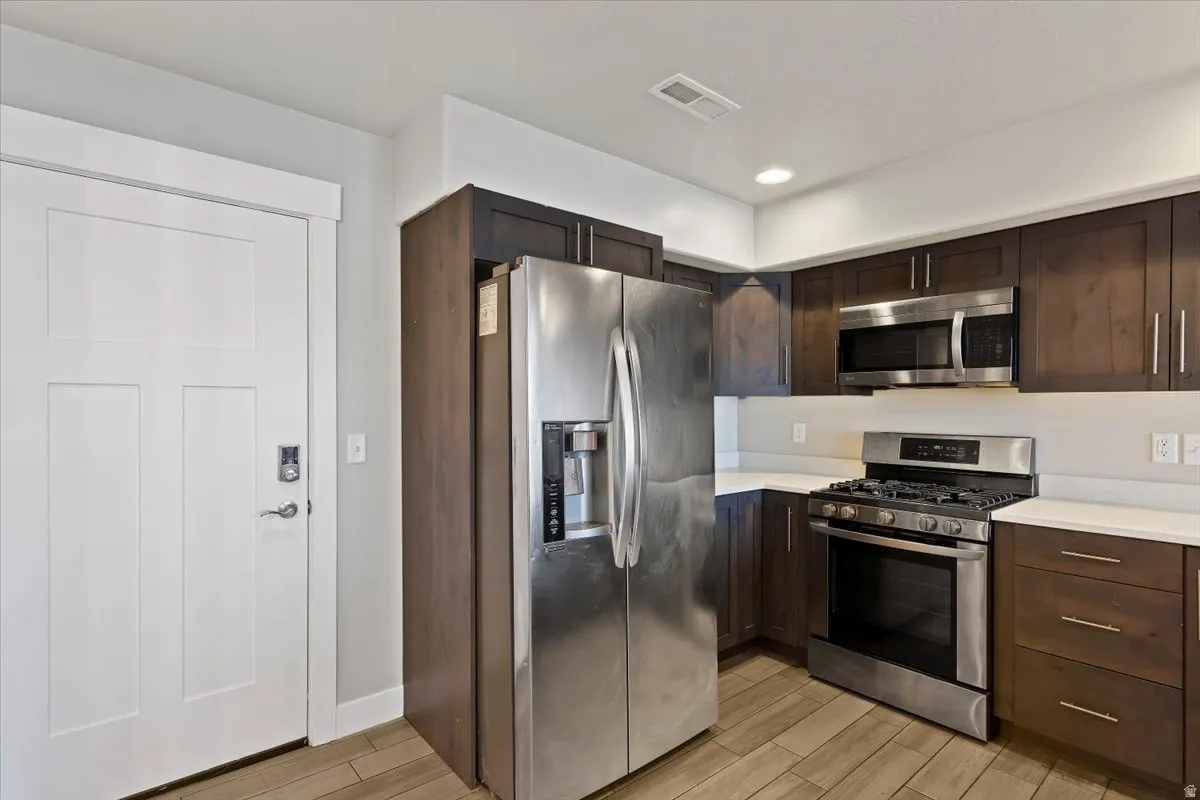 Kitchen with stainless steel appliances, dark wood finish cabinets, wood tiled floors, and recessed lighting