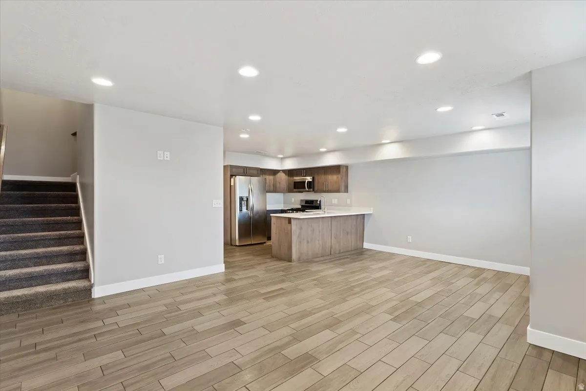 Kitchen with light countertops, open floor plan, a peninsula, stainless steel appliances, and wood tiled floors