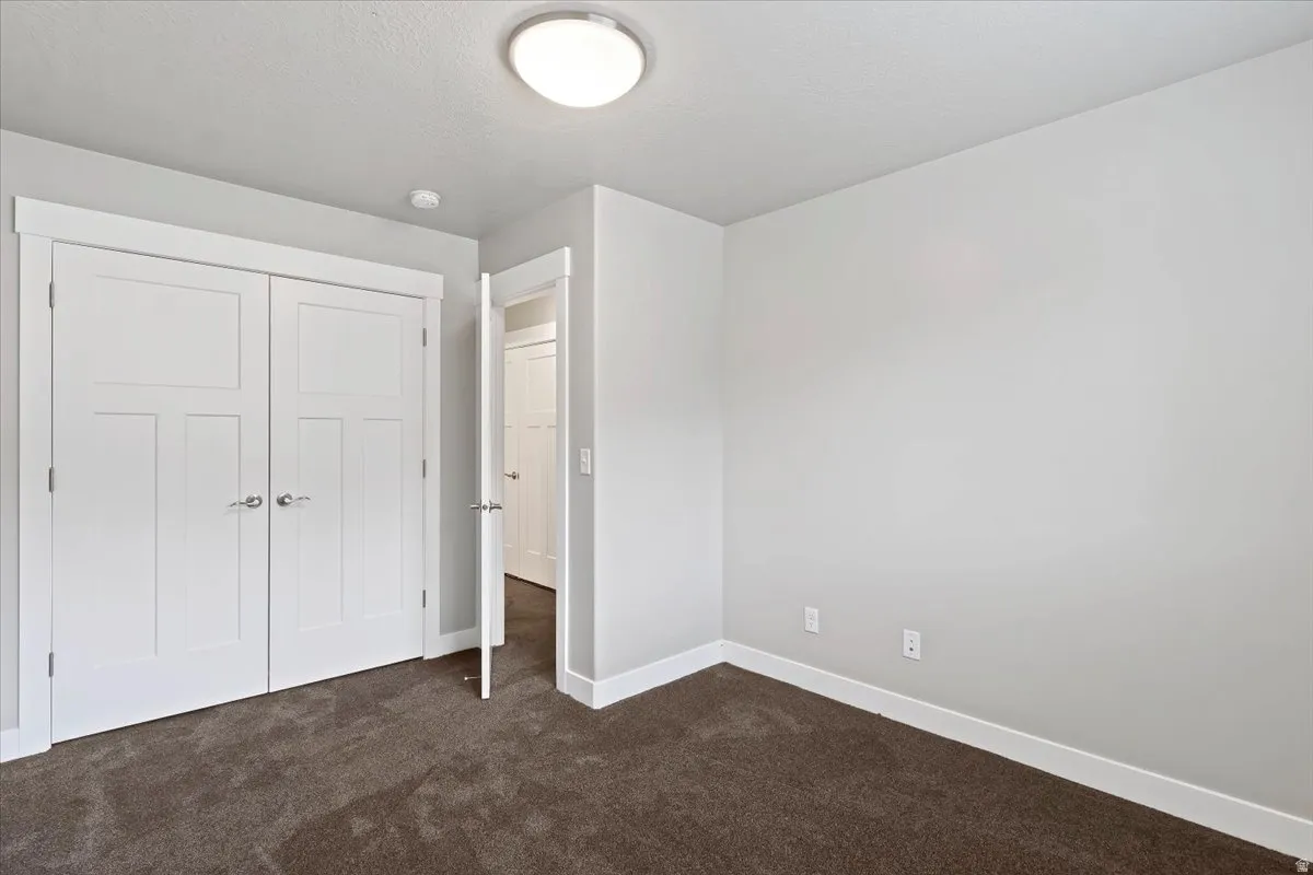 Unfurnished bedroom with dark carpet and a closet