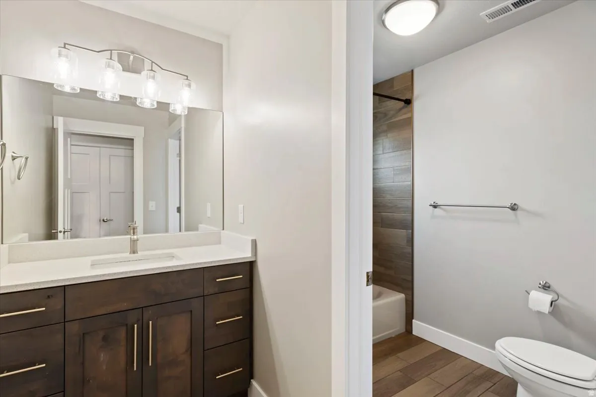 Full bathroom featuring vanity, light wood finished floors, and washtub / shower combination
