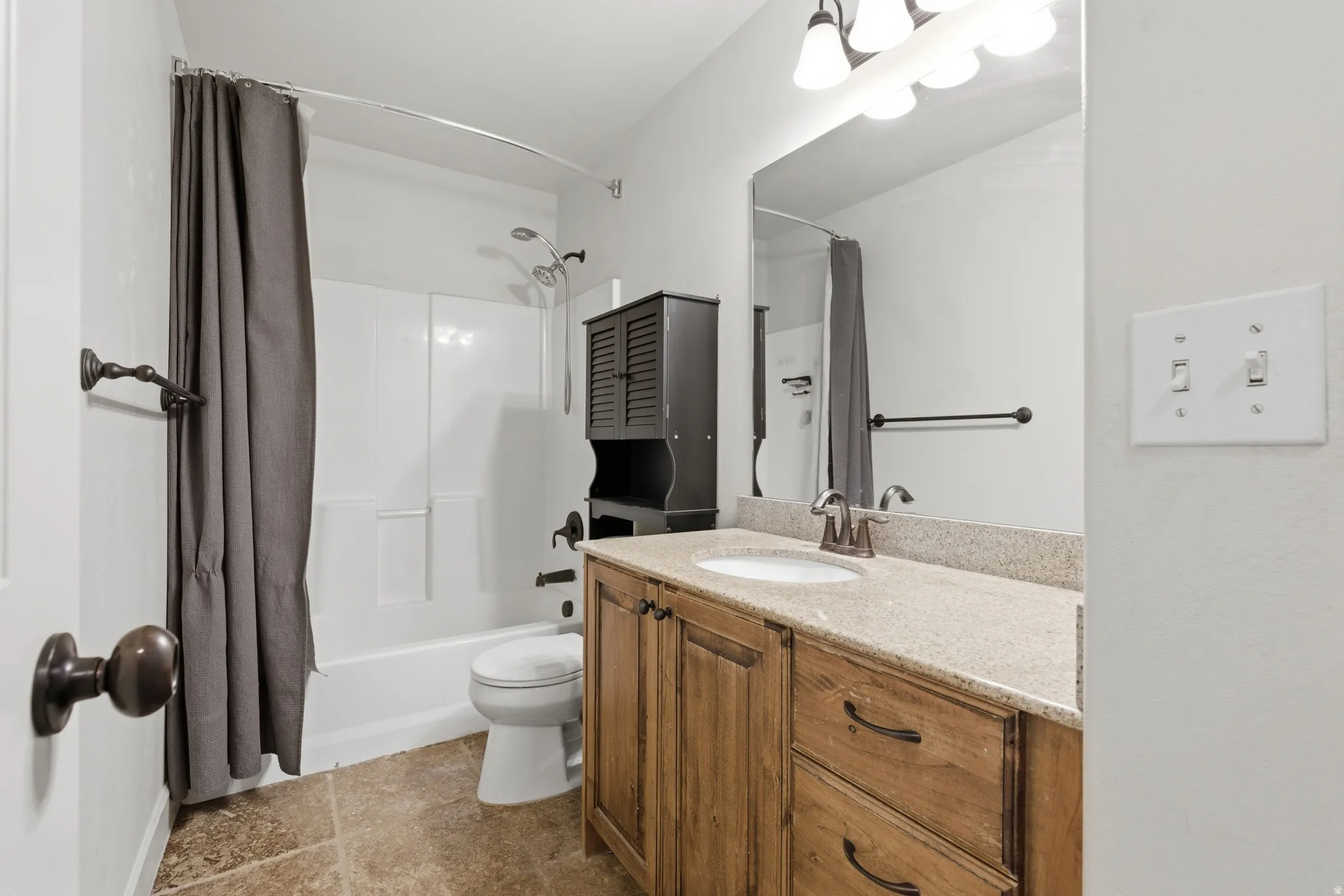 Bathroom featuring vanity and shower / bathtub combination with curtain