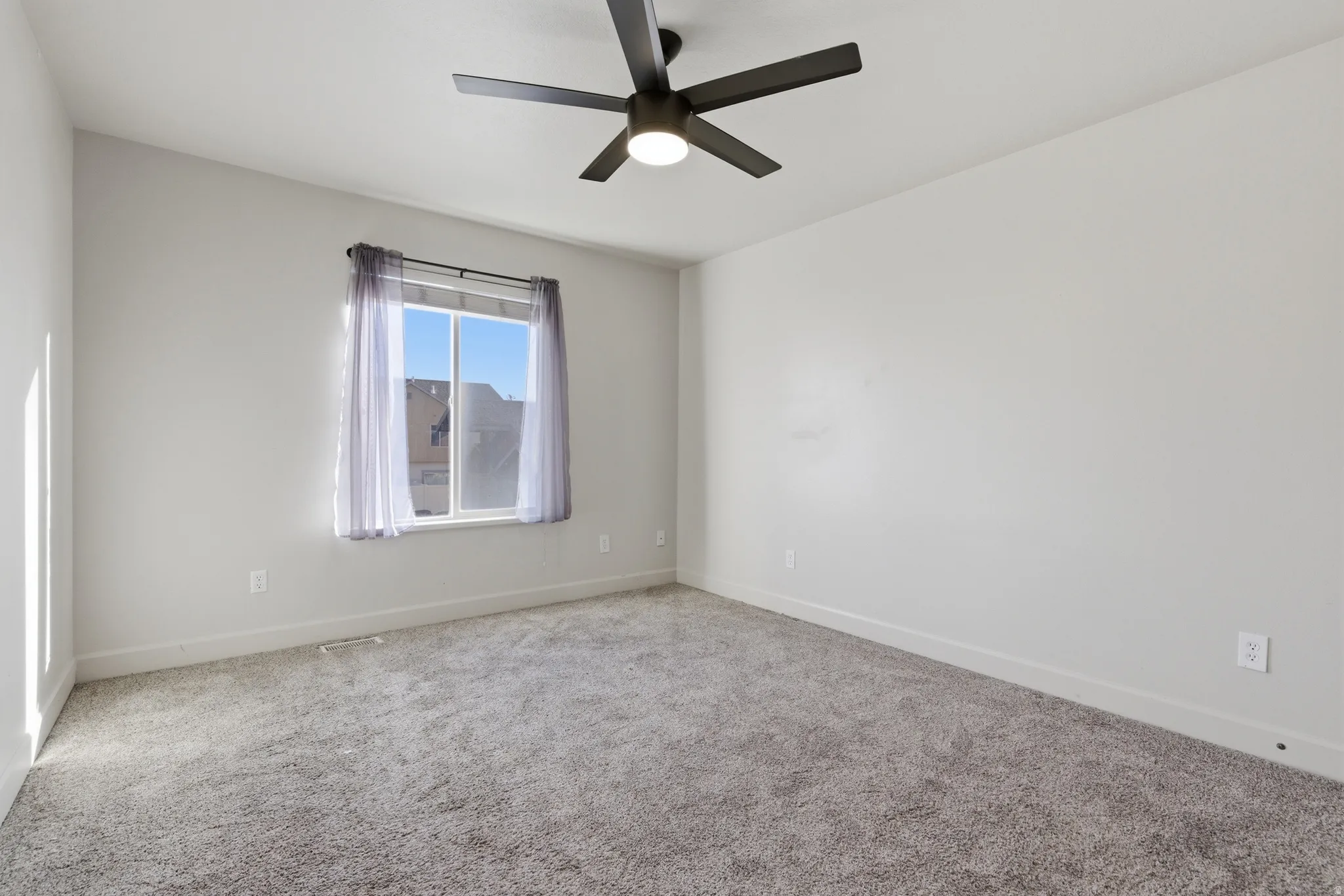 Spare room featuring carpet floors and a ceiling fan