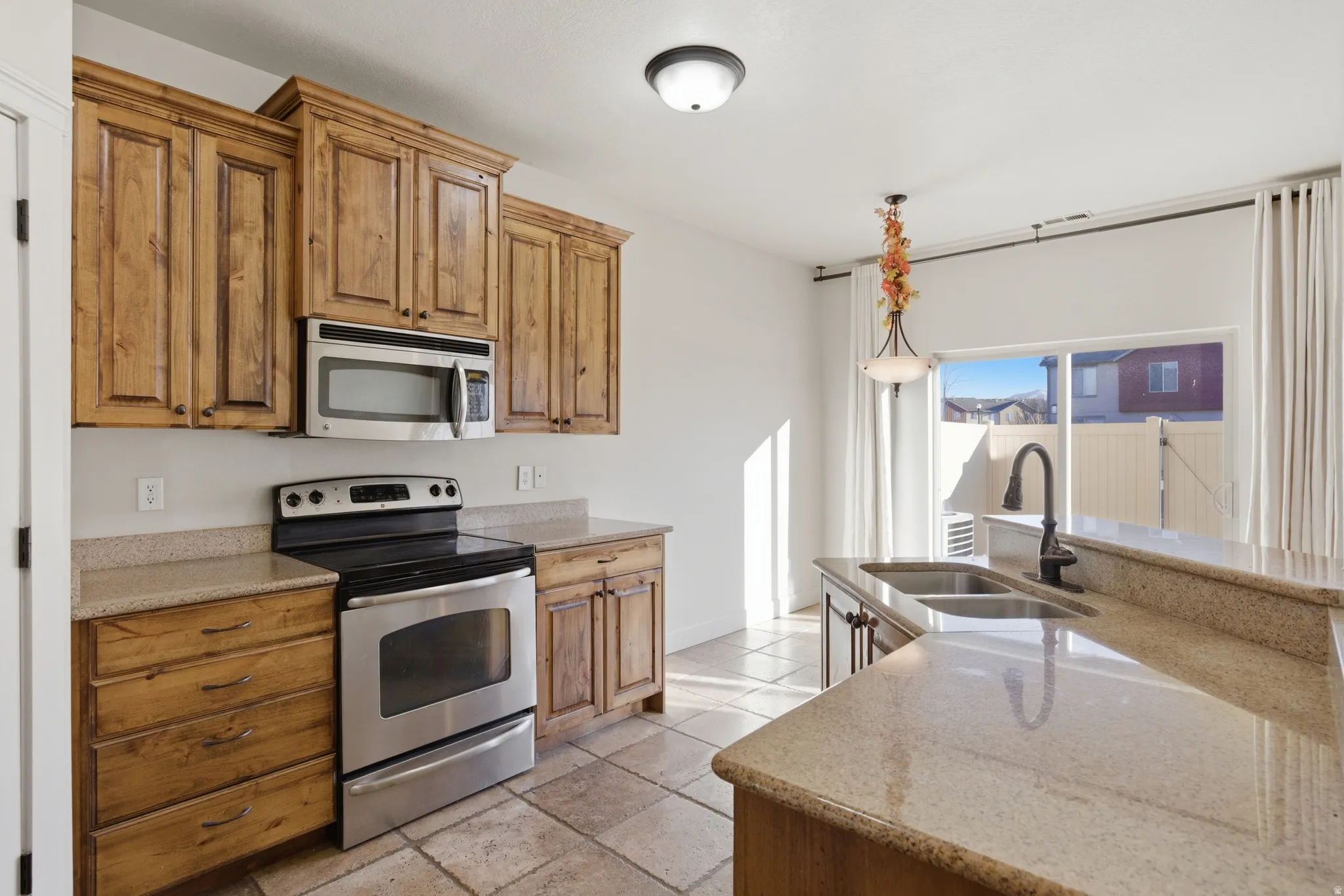 Kitchen featuring stainless steel appliances, light stone counters, and wood finish cabinets