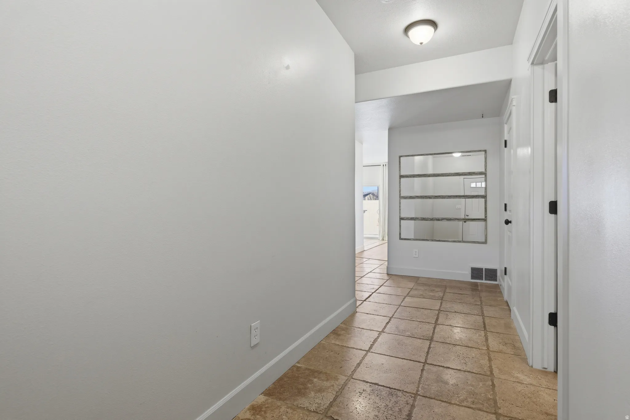 Hallway featuring stone tile flooring and baseboards