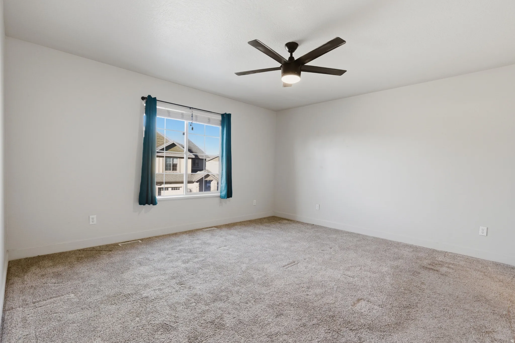 Carpeted empty room featuring baseboards and ceiling fan