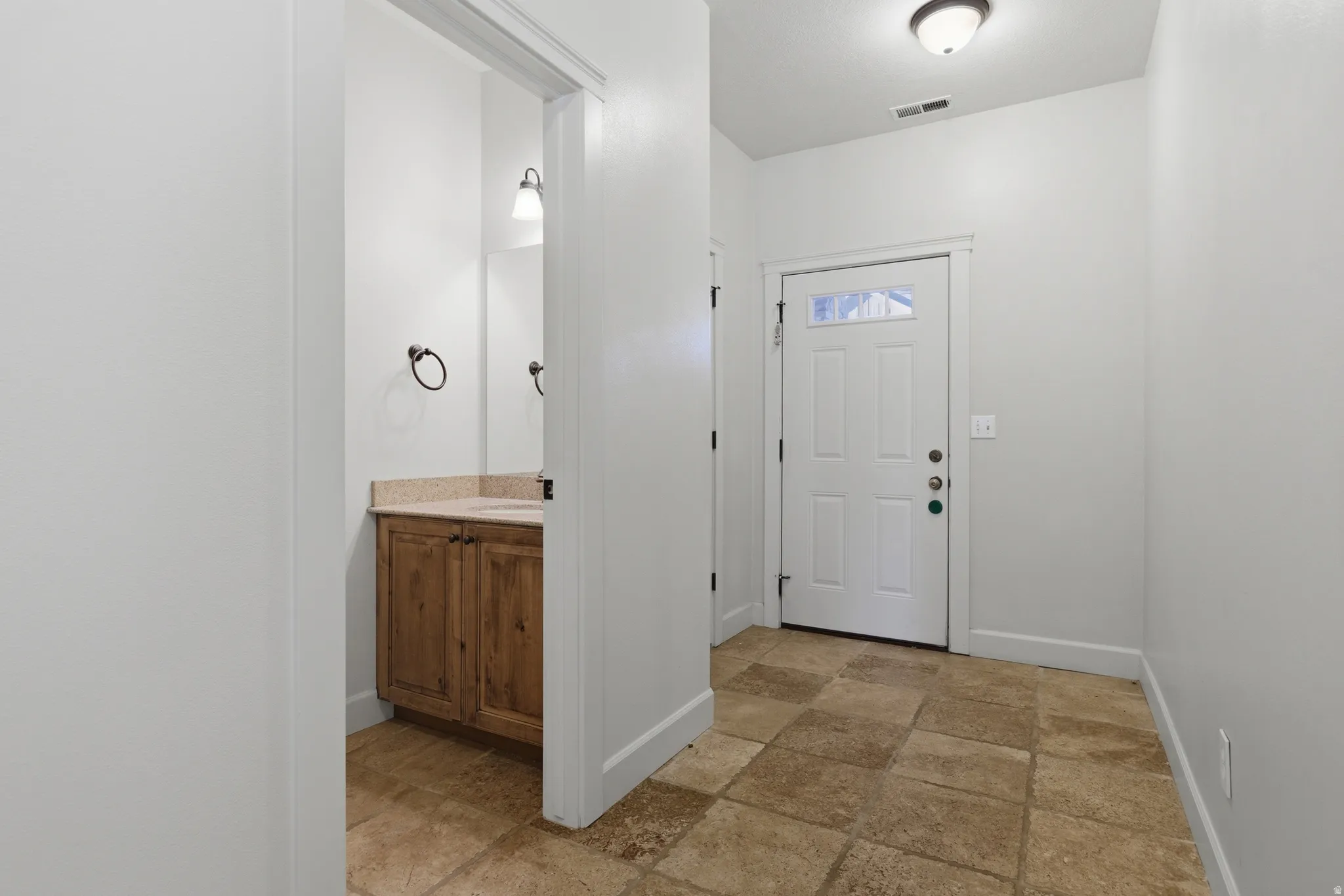 Entryway featuring light stone finish floors and baseboards