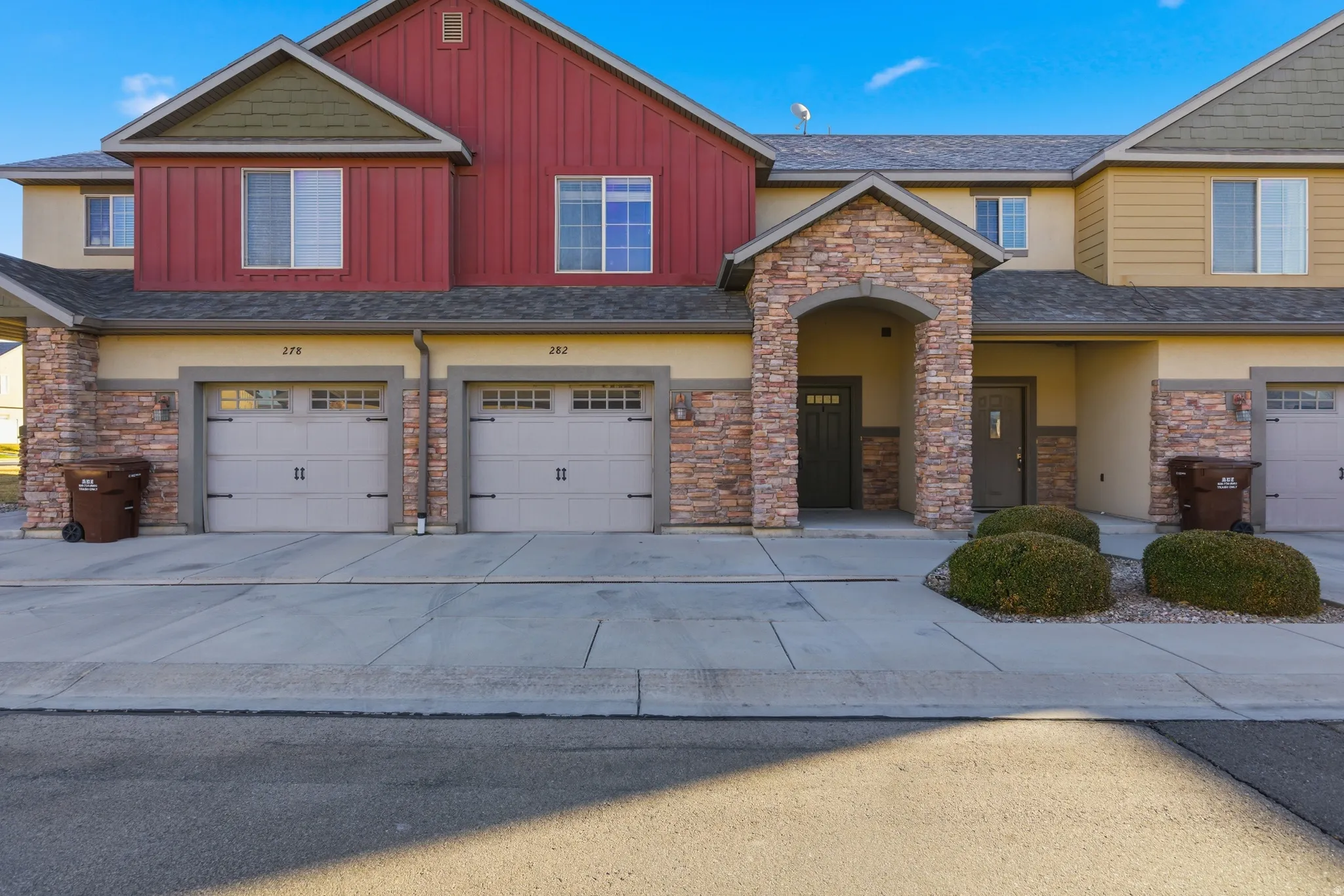 Craftsman inspired home featuring a garage, stone siding, driveway, stucco siding, and board and batten siding