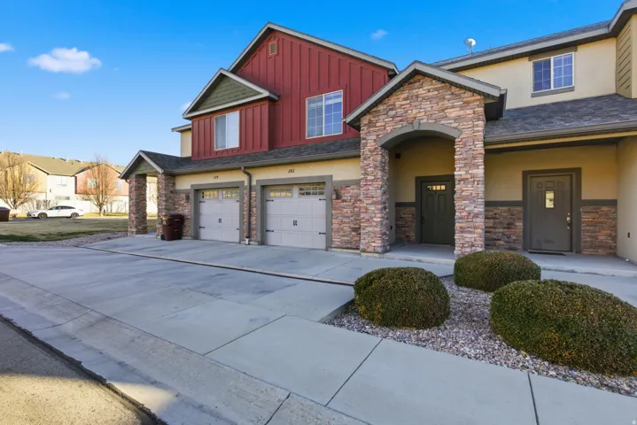 Craftsman-style house featuring an attached garage, stucco siding, board and batten siding, concrete driveway, and stone siding