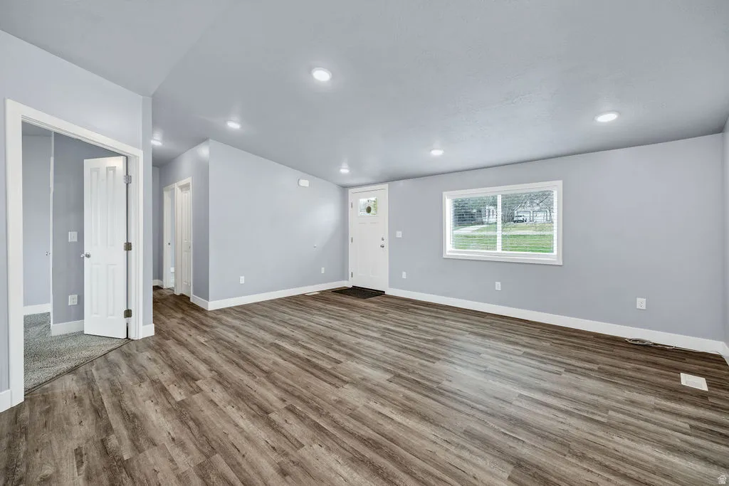 Unfurnished living room with dark wood-style flooring and recessed lighting